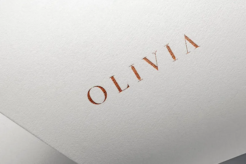 Olivia Boutique custom serif wordmark foil-stamped in copper on white cotton paper with generous letter spacing and refined geometric letterforms