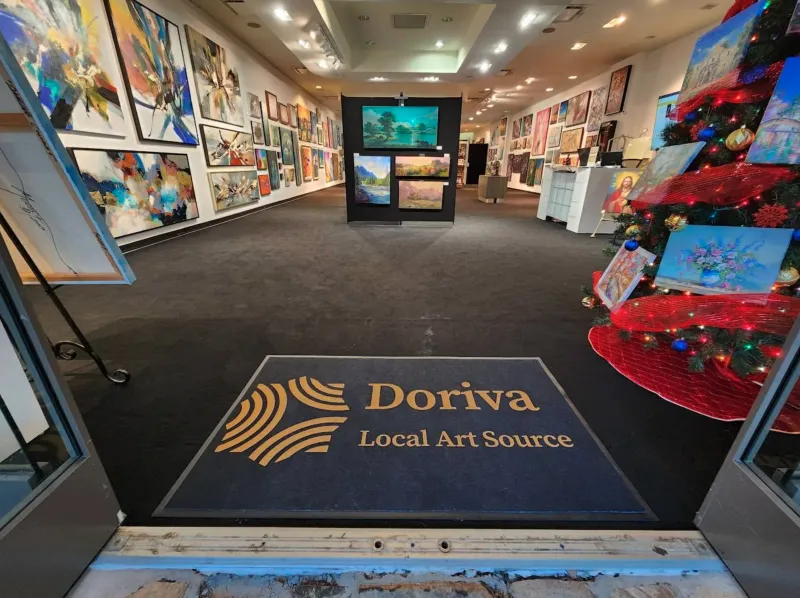 Doriva gallery interior viewed from entrance showing branded floor mat with gold ripple mark logo and walls lined with original artwork