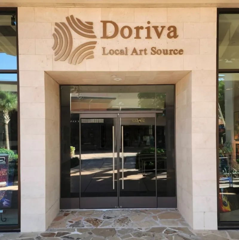 Doriva Local Art Source gallery entrance with raised dimensional lettering and ripple mark icon on stone facade