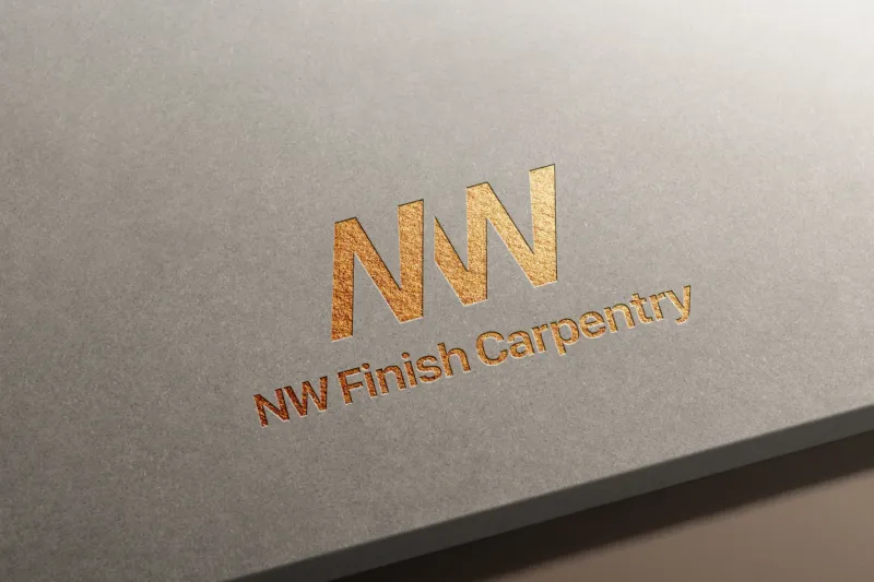 Gold foil embossed NW Finish Carpentry logo on smooth gray cardstock, showing the stylized NW monogram with saw blade-inspired angular letterforms above the company name in elegant metallic serif typography